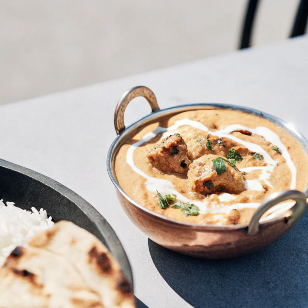 Chicken Tikka Masala in copper bowl with naan and rice